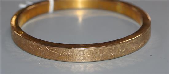 An engraved 9ct. gold bangle, 19.6 grams.